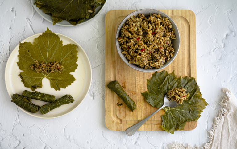Delicious dolma yalanji on a wooden board with rice and vegetables, top view.